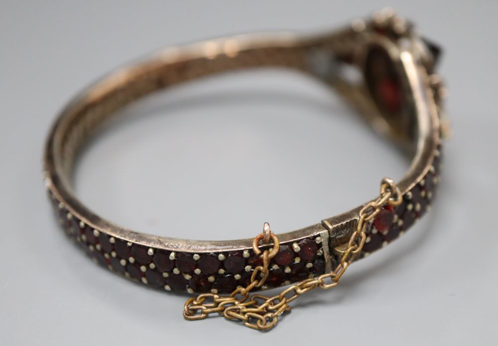 A Victorian gilt white metal and garnet set hinged bangle.